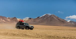Uyuni, Βολιβία, τζιπ στην έρημο με τα ηφαίστεια στο υπόβαθρο στοκ φωτογραφία Uyuni, Βολιβία, τζιπ στην έρημο με τα ηφαίστεια στο υπόβαθρο στοκ φωτογραφία