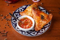 Uzbek Samsa In National Plate With Tomato Sauce On A Wooden Table. End Of The Eastern Baking. Royalty Free Stock Image
