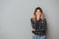 Uśmiechnięta atrakcyjna kobiety pozycja i mienie ręka przy jej podbródkiem obraz royalty free Uśmiechnięta atrakcyjna kobiety pozycja i mienie ręka przy jej podbródkiem obraz royalty free
