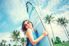 Uśmiechnięta kobieta z surfboard pozuje na tropikalnej plaży Surfingowiec dziewczyna w dużych okularach przeciwsłonecznych z dług obraz royalty free Uśmiechnięta kobieta z surfboard pozuje na tropikalnej plaży Surfingowiec dziewczyna w dużych okularach przeciwsłonecznych z dług obraz royalty free