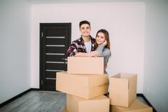 Uśmiechnięta para opiera na pudełkach w nowym domu Potomstwa dobierają się chodzenie nowy mieszkania przeniesienie wpólnie Obraz Stock Uśmiechnięta para opiera na pudełkach w nowym domu Potomstwa dobierają się chodzenie nowy mieszkania przeniesienie wpólnie Obraz Stock