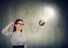 Uśmiechnięta piękna kobieta ma pomysł z żarówką nad jej głową obrazy stock Uśmiechnięta piękna kobieta ma pomysł z żarówką nad jej głową obrazy stock