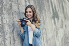 Uśmiechnięta szczęśliwa ładna kobieta patrzeje obrazki na jej cyfrowej kamerze Ubiera w przypadkowych ubraniach, szarości ściana fotografia stock Uśmiechnięta szczęśliwa ładna kobieta patrzeje obrazki na jej cyfrowej kamerze Ubiera w przypadkowych ubraniach, szarości ściana fotografia stock