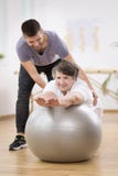Uśmiechniętej fizjoterapii studencka pomaga starsza kobieta kłaść na ćwiczy piłce podczas rehabilitacji obraz royalty free Uśmiechniętej fizjoterapii studencka pomaga starsza kobieta kłaść na ćwiczy piłce podczas rehabilitacji obraz royalty free