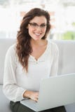 Uśmiechnięty bizneswomanu obsiadanie na leżance używać laptop Fotografia Stock Uśmiechnięty bizneswomanu obsiadanie na leżance używać laptop Fotografia Stock
