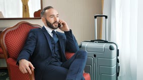 Uśmiechnięty męski biznesmen opowiada w eleganckim kostiumu mieć biznesu wywoławczego używa smartphone zbiory Uśmiechnięty męski biznesmen opowiada w eleganckim kostiumu mieć biznesu wywoławczego używa smartphone zbiory
