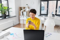 Uśmiechnięty ui projektant używa smartphone przy biurem obraz stock Uśmiechnięty ui projektant używa smartphone przy biurem obraz stock