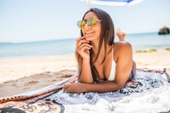 Vacation. Travel. Beautiful young woman with sunglasses relaxing under umbrella on the beach on sea background royalty free stock photography Vacation. Travel. Beautiful young woman with sunglasses relaxing under umbrella on the beach on sea background royalty free stock photography