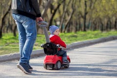 Vader die een rode duwauto met zijn peuterzoon duwen die het berijden op een de lentegang Papa en zoonsgang samen royalty-vrije stock foto's Vader die een rode duwauto met zijn peuterzoon duwen die het berijden op een de lentegang Papa en zoonsgang samen royalty-vrije stock foto's