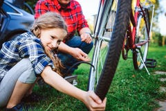 Vader en dochter bevestigende problemen met fiets openlucht in de zomer royalty-vrije stock afbeelding Vader en dochter bevestigende problemen met fiets openlucht in de zomer royalty-vrije stock afbeelding