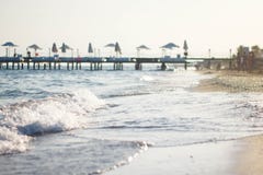 Vague blanche sur la plage sablonneuse Le rivage de la mer bleue contre la jetée Jetée par la mer en Turquie images libres de droits Vague blanche sur la plage sablonneuse Le rivage de la mer bleue contre la jetée Jetée par la mer en Turquie images libres de droits