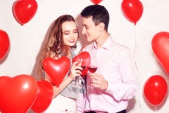 Valentine Beauty couple with red air balloons heart drinking red wine. Beautiful Happy Young woman and man hugs. Joyful lover stock photography Valentine Beauty couple with red air balloons heart drinking red wine. Beautiful Happy Young woman and man hugs. Joyful lover stock photography