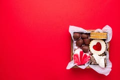 Valentines Day sweets and cookies in wooden box on red background. Chocolate, meringue, marshmallow, linzer cookies, gingerbread.