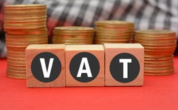 Value added Tax on wooden dice and currency coins in background Royalty Free Stock Photography Value added Tax on wooden dice and currency coins in background Royalty Free Stock Photography