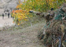 Van de camouflagejager of militair het verbergen in struiken in camouflage stock afbeelding Van de camouflagejager of militair het verbergen in struiken in camouflage stock afbeelding
