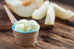 Vaniljglass med en smak av melon i en bunke på den gamla trätabellen På bakgrunden av den skivade nya melon royaltyfri foto Vaniljglass med en smak av melon i en bunke på den gamla trätabellen På bakgrunden av den skivade nya melon royaltyfri foto