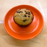 Vanilla with chocolate chips muffin on a bright orange plate royalty free stock image Vanilla with chocolate chips muffin on a bright orange plate royalty free stock image