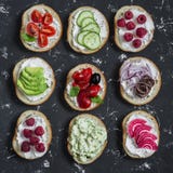 Varietà di panini - i panini con formaggio, i pomodori, acciughe, hanno arrostito i peperoni, i lamponi, l'avocado, il patè del f fotografia stock Varietà di panini - i panini con formaggio, i pomodori, acciughe, hanno arrostito i peperoni, i lamponi, l'avocado, il patè del f fotografia stock