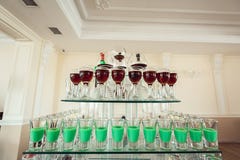 Variété de tirs verts et rouges colorés d'alcool en petits verres se tenant dans la rangée sur un support en verre photos stock Variété de tirs verts et rouges colorés d'alcool en petits verres se tenant dans la rangée sur un support en verre photos stock