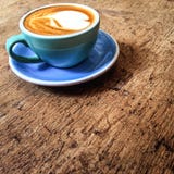 Varmt konstLattekaffe i en kopp i coffee shop på trätabellintelligens arkivfoto Varmt konstLattekaffe i en kopp i coffee shop på trätabellintelligens arkivfoto