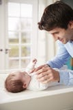 Vater-Playing With Newborn-Baby, das auf ändernder Tabelle liegt Stockfotografie Vater-Playing With Newborn-Baby, das auf ändernder Tabelle liegt Stockfotografie