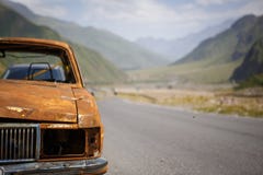 Vecchia automobile bruciata arrugginita sul bordo della strada di Georgia, circondato dalle montagne e dalla bellezza immagini stock libere da diritti Vecchia automobile bruciata arrugginita sul bordo della strada di Georgia, circondato dalle montagne e dalla bellezza immagini stock libere da diritti