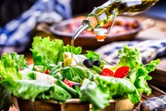 Vegetable lettuce salad. Olive oil pouring into bowl of salad. Italian Mediterranean or Greek cuisine. Vegetarian vegan food stock images Vegetable lettuce salad. Olive oil pouring into bowl of salad. Italian Mediterranean or Greek cuisine. Vegetarian vegan food stock images