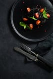 Vegetarisk matr?tt, svart spagetti med basilika och k?rsb?rsr?da tomater Svart bakgrund, b?sta sikt royaltyfri fotografi Vegetarisk matr?tt, svart spagetti med basilika och k?rsb?rsr?da tomater Svart bakgrund, b?sta sikt royaltyfri fotografi