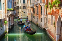 Venice, gondolas sailing tourists along narrow canals, popular tourist attraction
