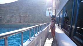 Verano, mar, mujer morena joven atractiva hermosa que lleva un bañador, sombrero del sol y gafas de sol, caminando a lo largo de almacen de video Verano, mar, mujer morena joven atractiva hermosa que lleva un bañador, sombrero del sol y gafas de sol, caminando a lo largo de almacen de video
