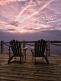 Verbazende purpere oever van het meerzonsondergang met twee stoelen op een dok royalty-vrije stock foto Verbazende purpere oever van het meerzonsondergang met twee stoelen op een dok royalty-vrije stock foto