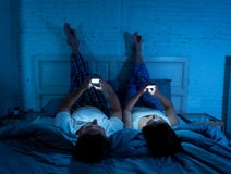 Verbinden Sie an den Handys im Bett spät nachts Soziales Netz, Spiele und Internetanschluss genießend lizenzfreies stockbild Verbinden Sie an den Handys im Bett spät nachts Soziales Netz, Spiele und Internetanschluss genießend lizenzfreies stockbild