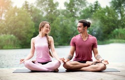 Verbinden Sie übendes Yoga und das Betrachten einander in der Natur nahe dem Fluss Paarmeditation lizenzfreie stockfotografie Verbinden Sie übendes Yoga und das Betrachten einander in der Natur nahe dem Fluss Paarmeditation lizenzfreie stockfotografie