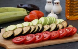 Verduras del corte: el calabacín, las berenjenas y los tomates están situados en un tablero de madera en un fondo oscuro imagen de archivo libre de regalías Verduras del corte: el calabacín, las berenjenas y los tomates están situados en un tablero de madera en un fondo oscuro imagen de archivo libre de regalías