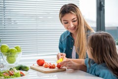 Verdure allegre di taglio della madre insieme al suo bambino immagine stock Verdure allegre di taglio della madre insieme al suo bambino immagine stock