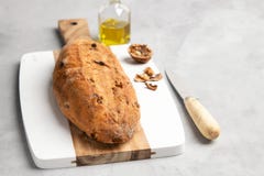 Vers gezond brood met okkernoten en rozijnen op scherpe raad op grijze steenachtergrond stock foto Vers gezond brood met okkernoten en rozijnen op scherpe raad op grijze steenachtergrond stock foto