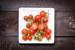 Verse tomaten op witte plaat met houten donkere achtergrond stock fotografie Verse tomaten op witte plaat met houten donkere achtergrond stock fotografie