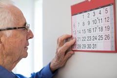 Verwarde Hogere Mens die met Zwakzinnigheid Muurkalender bekijken stock foto Verwarde Hogere Mens die met Zwakzinnigheid Muurkalender bekijken stock foto