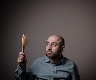 Verwirrter kahler Mann mit Haarbürste stockfoto Verwirrter kahler Mann mit Haarbürste stockfoto