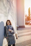 Vetri d'uso della ragazza attraente in un cappotto che cammina un giorno soleggiato fotografie stock libere da diritti Vetri d'uso della ragazza attraente in un cappotto che cammina un giorno soleggiato fotografie stock libere da diritti