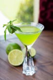 Vetro di rinfresco della limonata fredda della calce con la menta su una tavola di legno in un ristorante con una decorazione cre fotografia stock libera da diritti Vetro di rinfresco della limonata fredda della calce con la menta su una tavola di legno in un ristorante con una decorazione cre fotografia stock libera da diritti