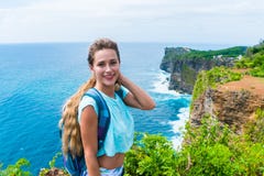 Viaggiatore femminile grazioso con una condizione dello zaino sull'orlo di una scogliera e sorridere sulla macchina fotografica B fotografia stock libera da diritti Viaggiatore femminile grazioso con una condizione dello zaino sull'orlo di una scogliera e sorridere sulla macchina fotografica B fotografia stock libera da diritti