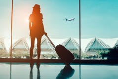 Viaje de la mujer de la silueta con el equipaje que mira sin la ventana el international del terminal de aeropuerto o el adolesce Viaje de la mujer de la silueta con el equipaje que mira sin la ventana el international del terminal de aeropuerto o el adolesce