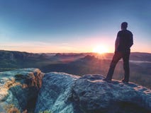 Viandante dell'uomo al picco di montagna Alba piacevole nel paesaggio nebbioso fotografia stock Viandante dell'uomo al picco di montagna Alba piacevole nel paesaggio nebbioso fotografia stock