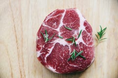 Viande de porc crue/bifteck frais prêt pour le gril avec le romarin d'épices sur le fond en bois de planche à découper photographie stock Viande de porc crue/bifteck frais prêt pour le gril avec le romarin d'épices sur le fond en bois de planche à découper photographie stock
