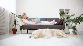 Vida de animales domésticos nacionales en la familia la madre lee el libro a los niños el golden retriever miente en el piso almacen de video Vida de animales domésticos nacionales en la familia la madre lee el libro a los niños el golden retriever miente en el piso almacen de video