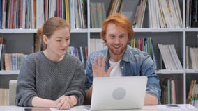 Video chiacchierata online dalle coppie, compagni di squadra sul computer portatile in ufficio fotografia stock libera da diritti Video chiacchierata online dalle coppie, compagni di squadra sul computer portatile in ufficio fotografia stock libera da diritti