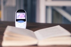 Videobabymonitor met beeld van slaapbaby op het scherm op de lijst met open boek De moeder ontspant tijd tijdens kind dags stock fotografie Videobabymonitor met beeld van slaapbaby op het scherm op de lijst met open boek De moeder ontspant tijd tijdens kind dags stock fotografie