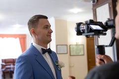 Videography of the wedding with the groom in a blue suit using the camera, operator and stabilizer
