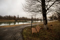 Videz le banc au parc près de l'étang par jour brumeux, scène froide minimalistic de saison banc au lac dans le brouillard dans l Image stock Videz le banc au parc près de l'étang par jour brumeux, scène froide minimalistic de saison banc au lac dans le brouillard dans l Image stock